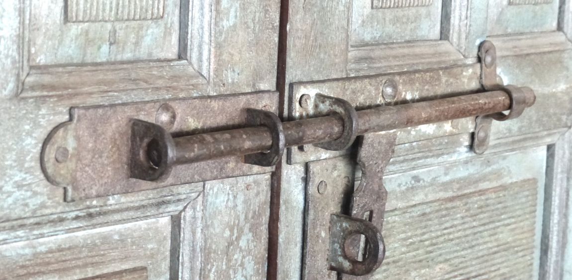 Rusty metal barrel bolt lock on weathered wooden double doors
