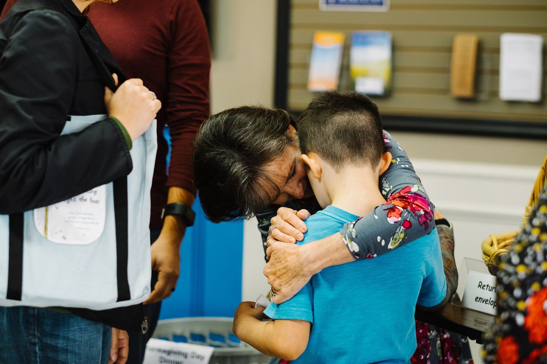 a woman is hugging a young boy in a room .