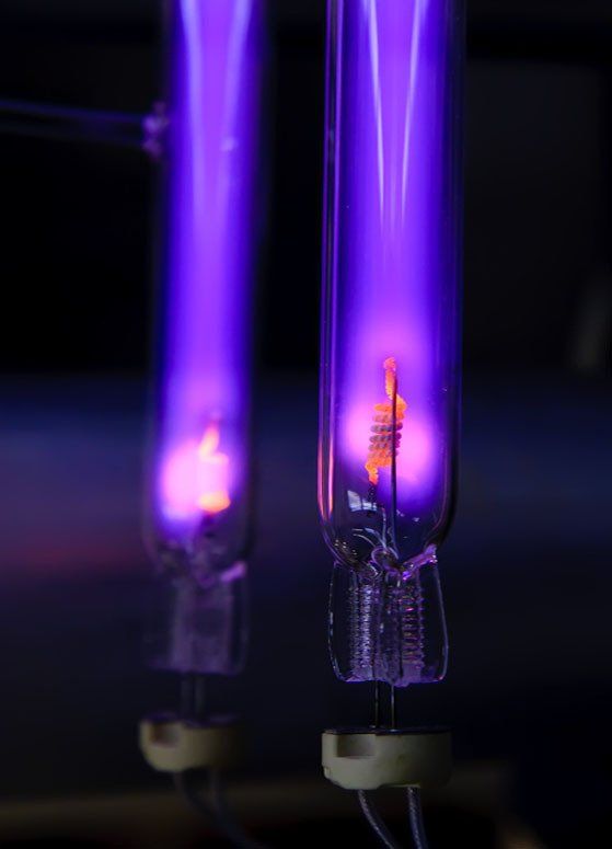 Two glowing purple UV light tubes with orange filaments, electrical components visible.