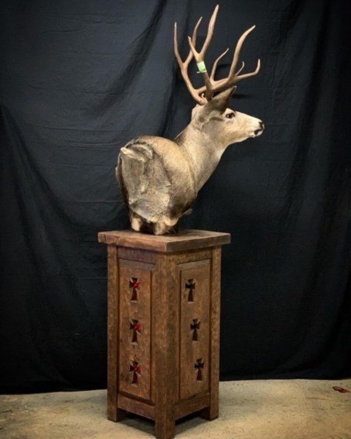 A statue of a deer sitting on top of a wooden pedestal