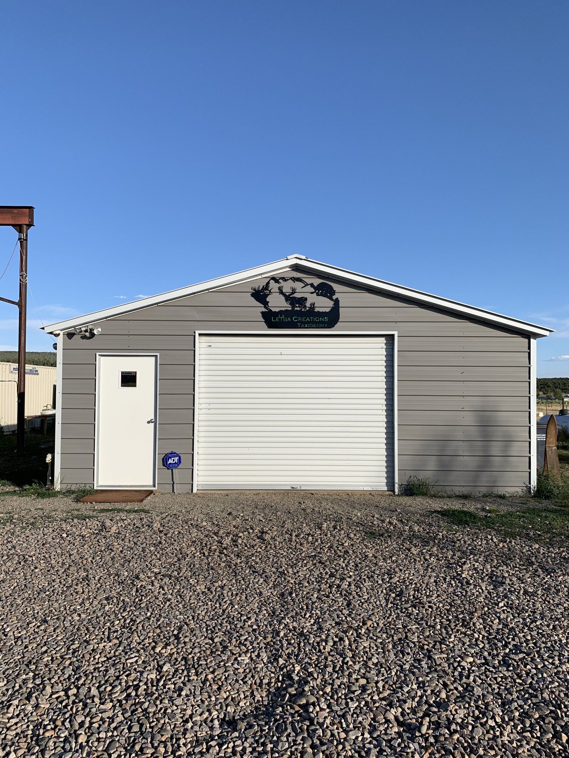 A garage with a white door is sitting on top of a gravel lot.