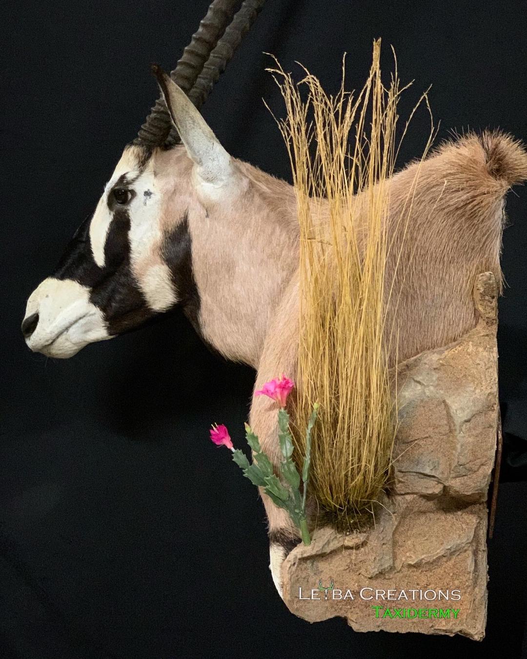 A stuffed animal of an antelope with a pink flower in its mouth