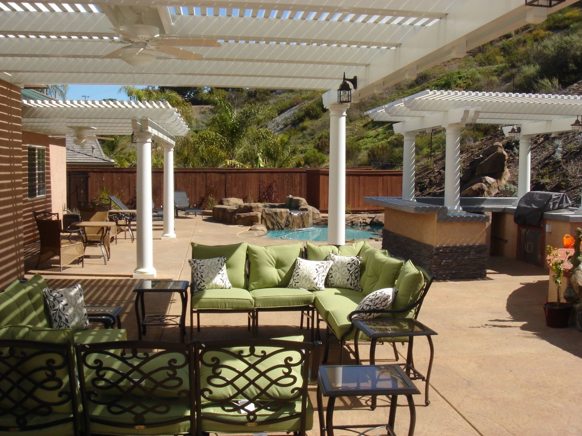 A patio with a couch and chairs under a pergola