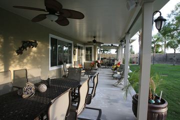 A patio with a table, chairs, and a ceiling fan