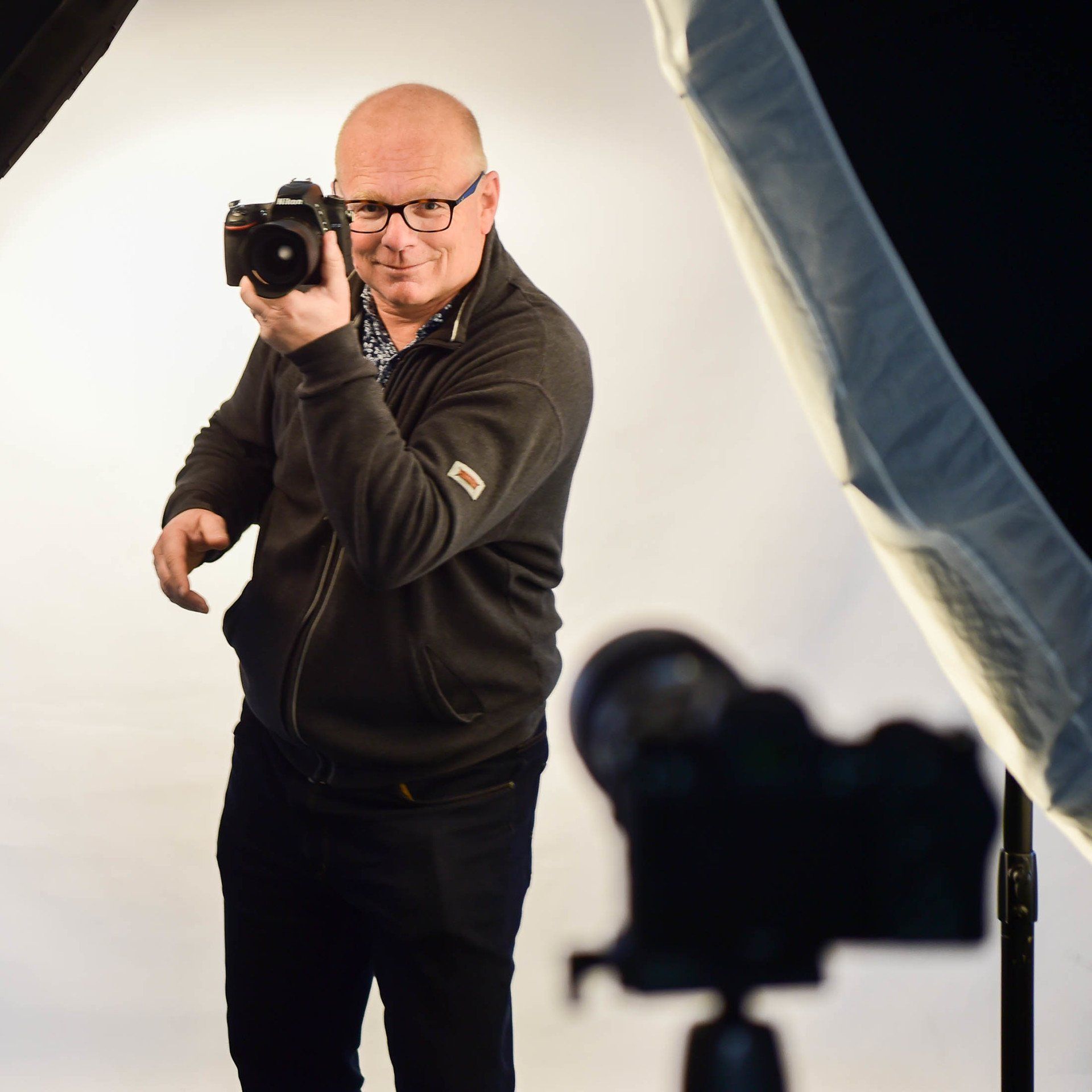 Een man in een zwart jasje maakt een foto met een camera