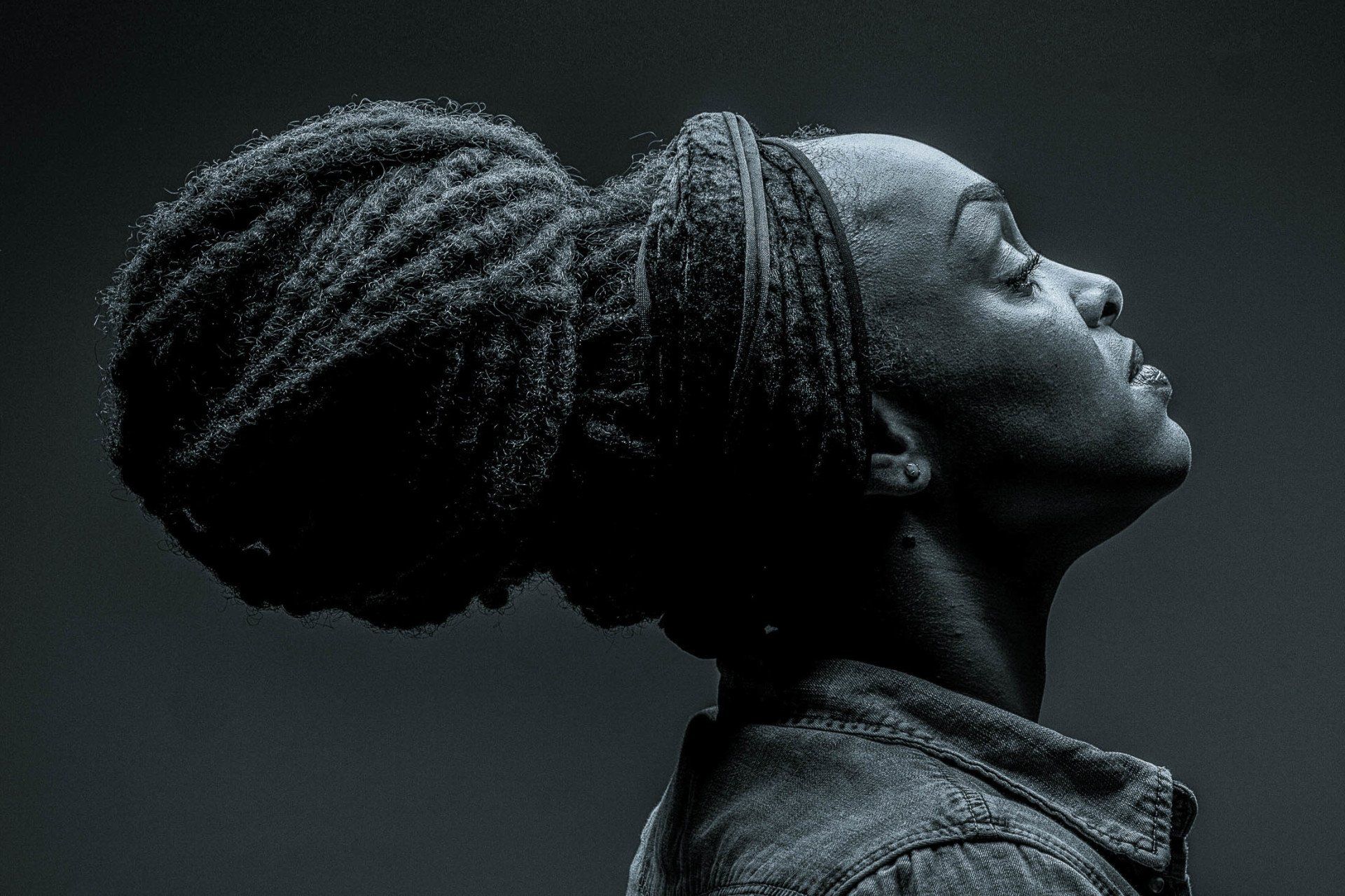 Een vrouw met dreadlocks in een knot kijkt omhoog.