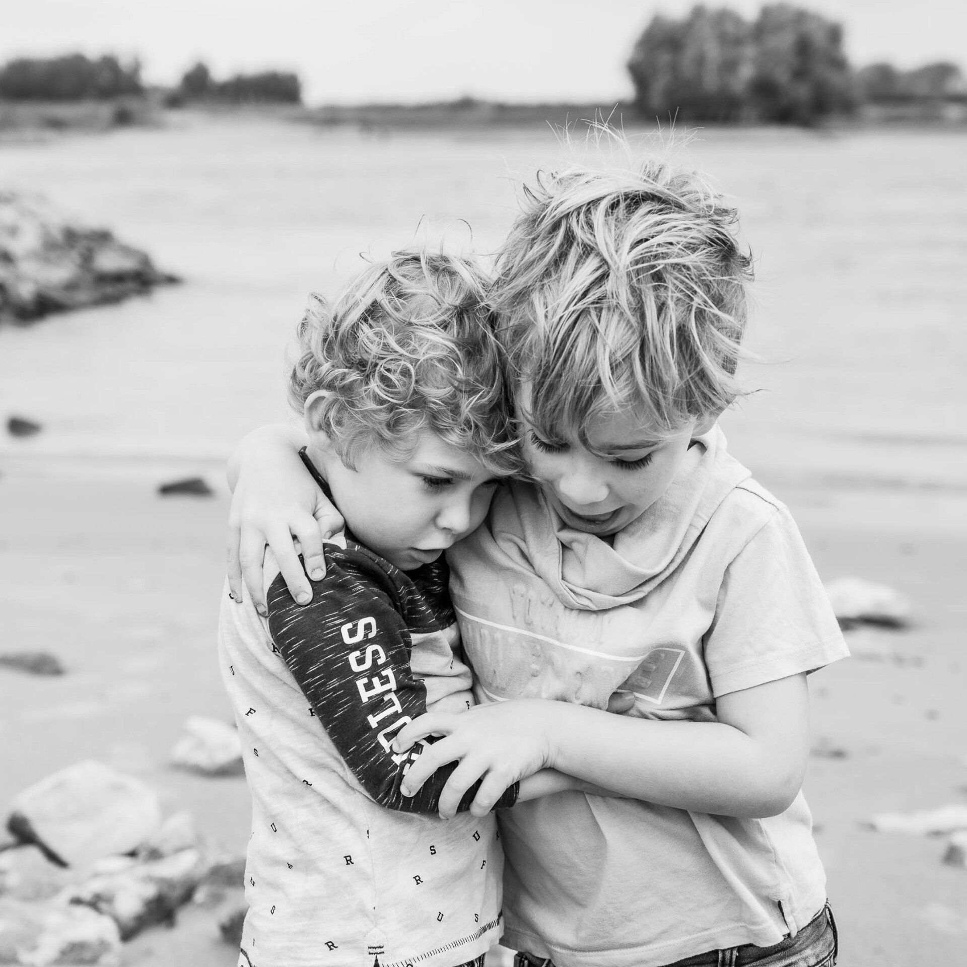 Twee jonge jongens omhelzen elkaar op het strand.