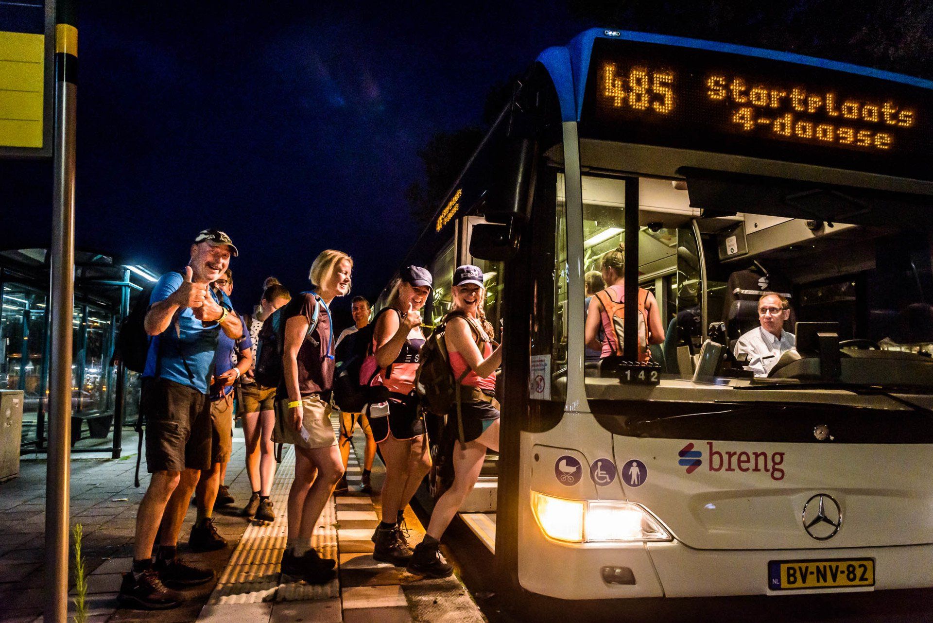 Een groep mensen stapt 's nachts in een bus.
