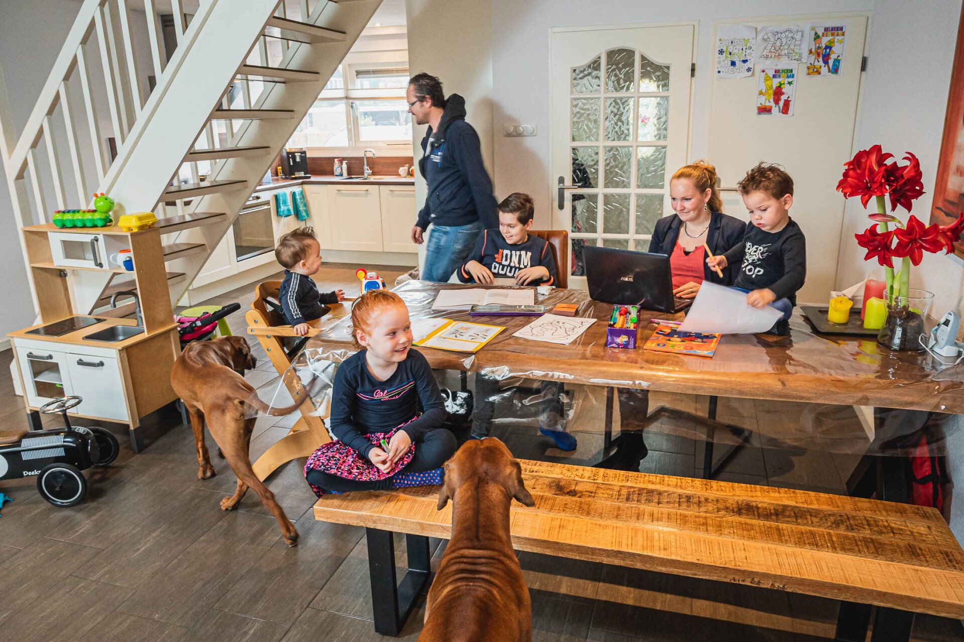 Een gezin zit met een hond aan tafel in de woonkamer.