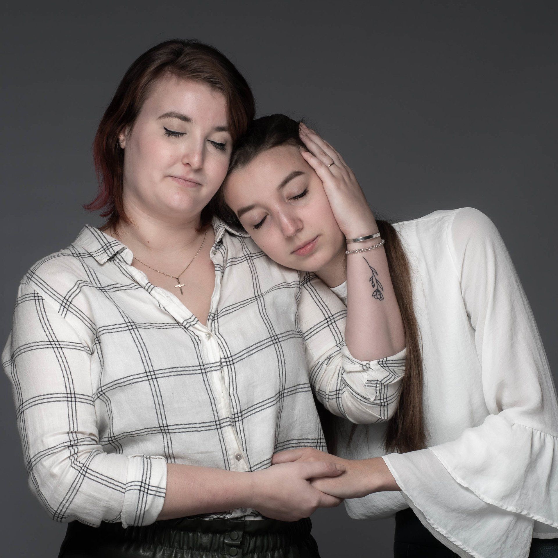 Een vrouw met een tatoeage op haar pols omhelst een andere vrouw