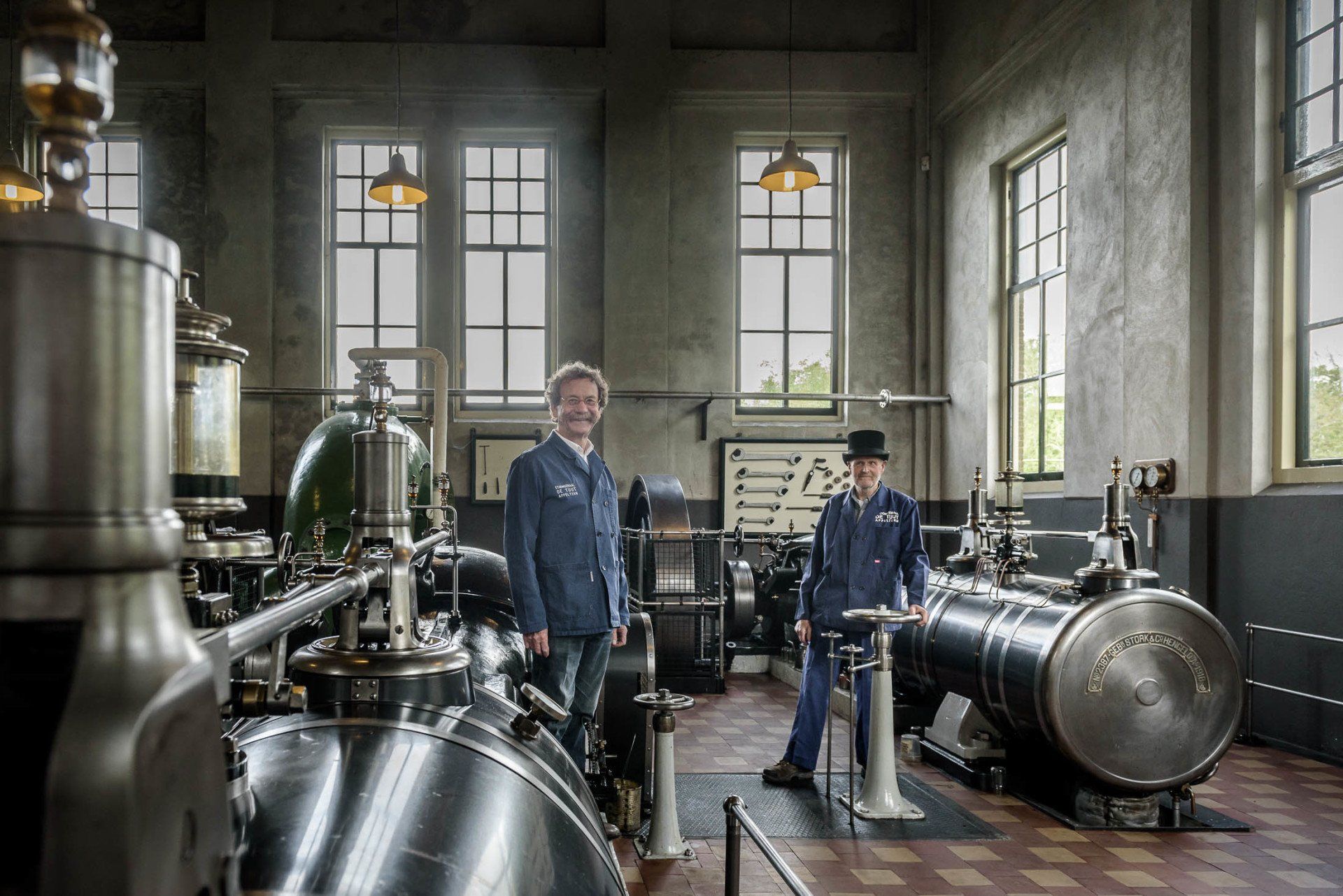 Twee mannen staan voor een machine in een fabriek.