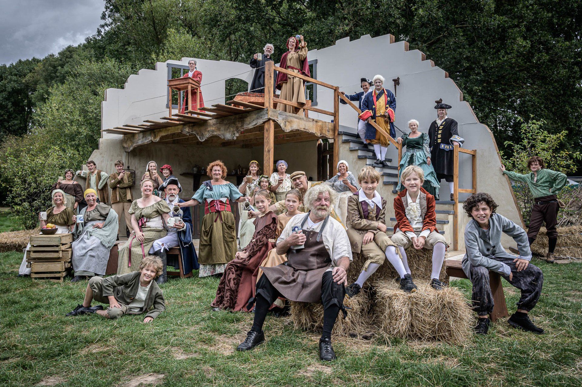 Een grote groep mensen poseert voor een foto voor een gebouw.