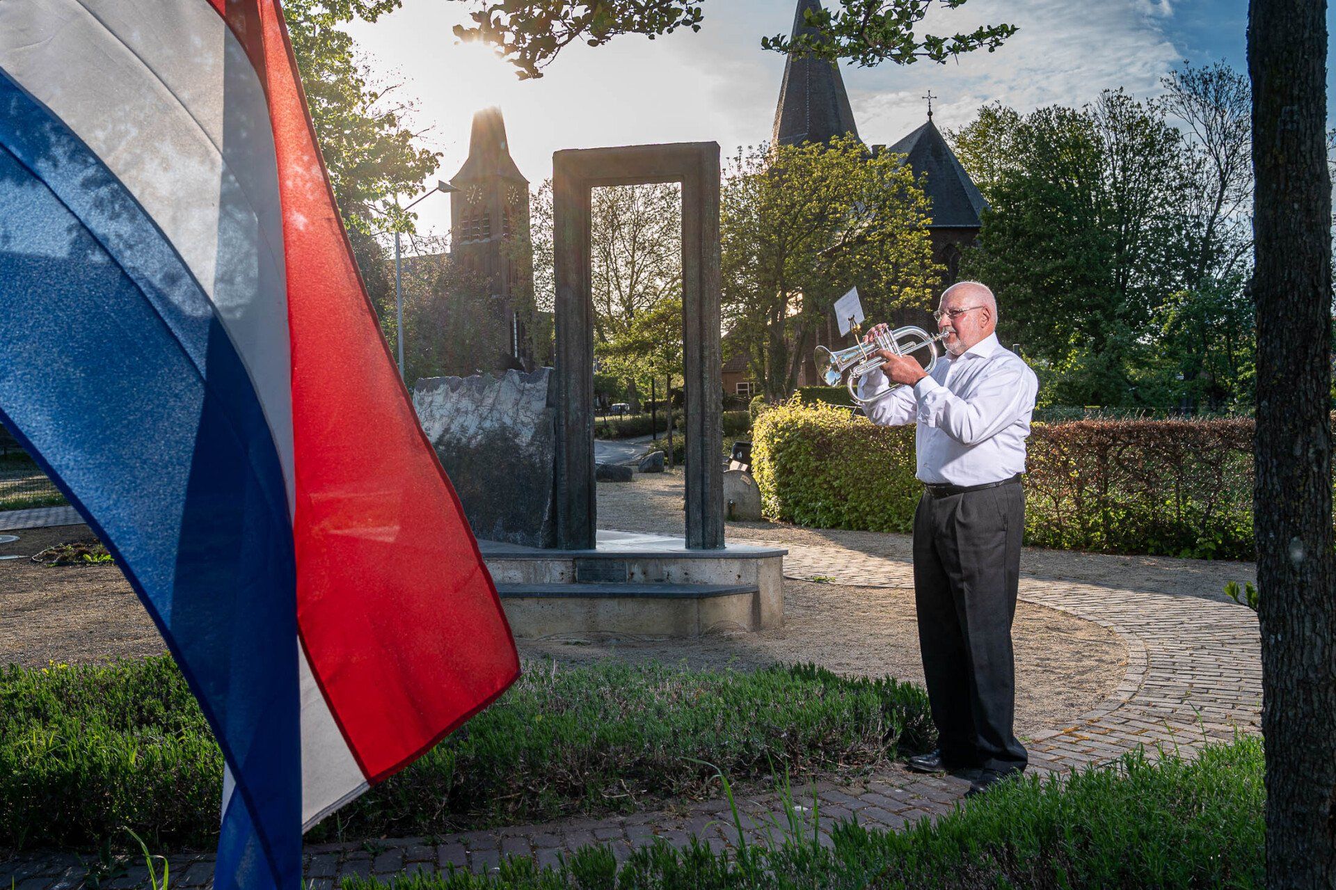 Een man speelt op een trompet voor een vlag.