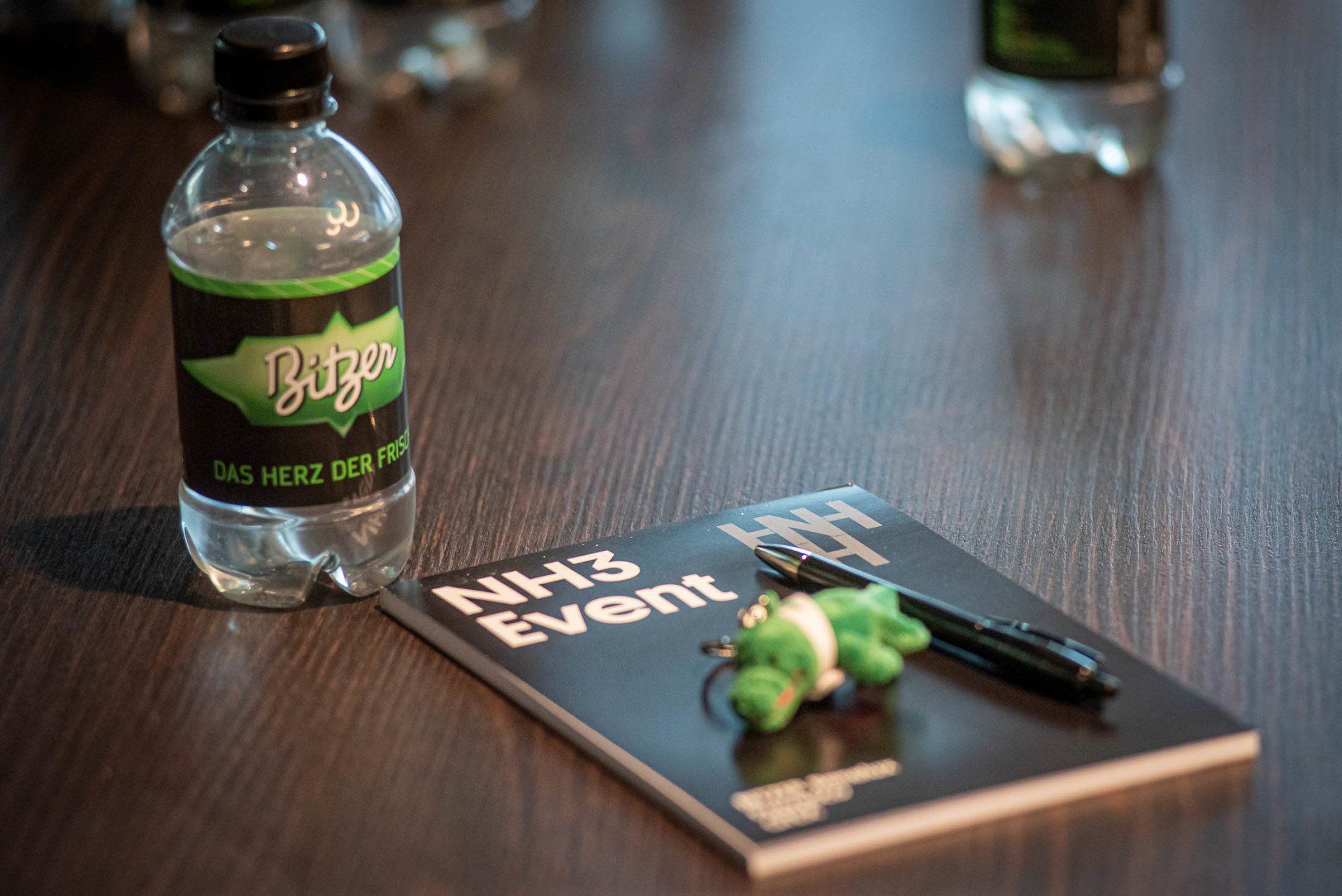 Een fles water en een notitieboekje met een pen op een tafel.