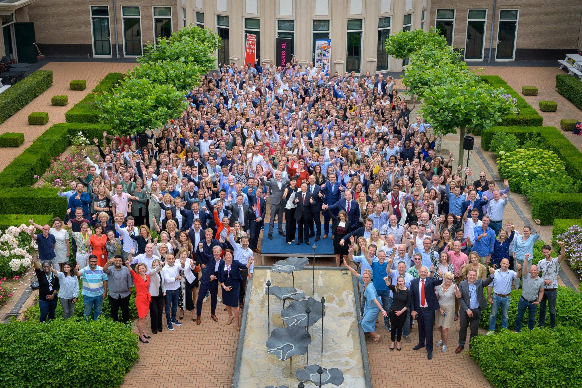 Een grote groep mensen poseert voor een foto voor een fontein.
