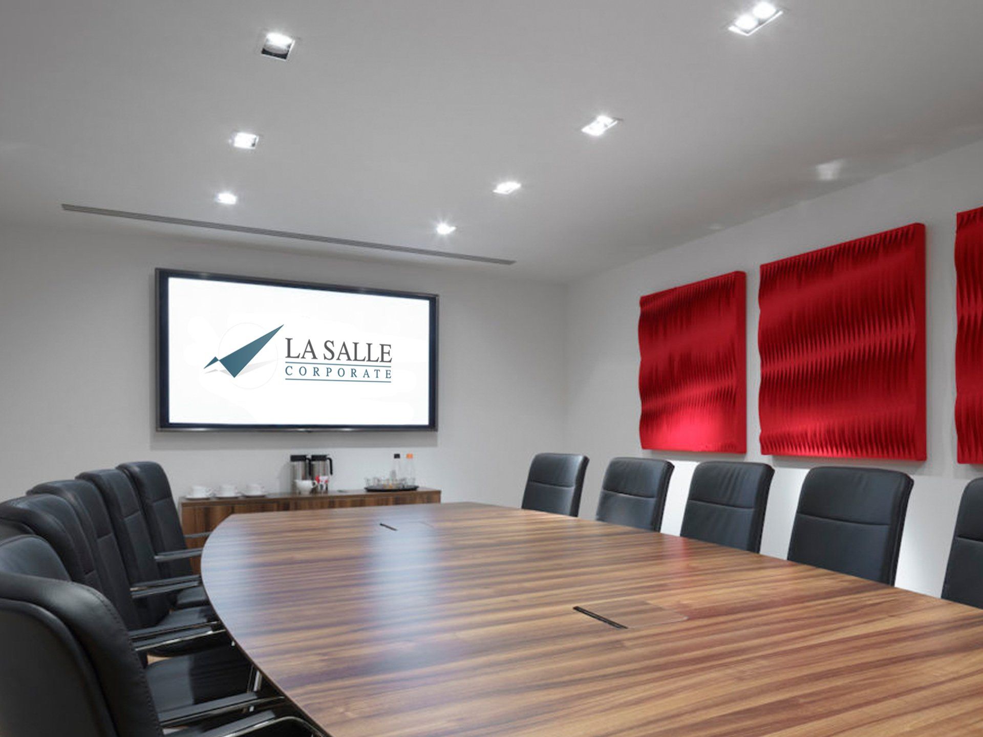 Modern conference room with oval wooden table, black chairs, wall screen, and red acoustic panels
