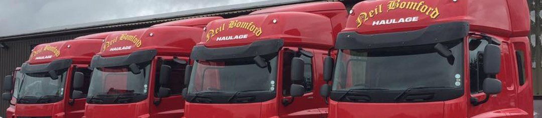 Row of red delivery trucks with black windshields parked side by side