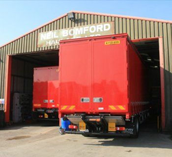 Red trucks parked in open garage bays at Neil Bimford haulage depot