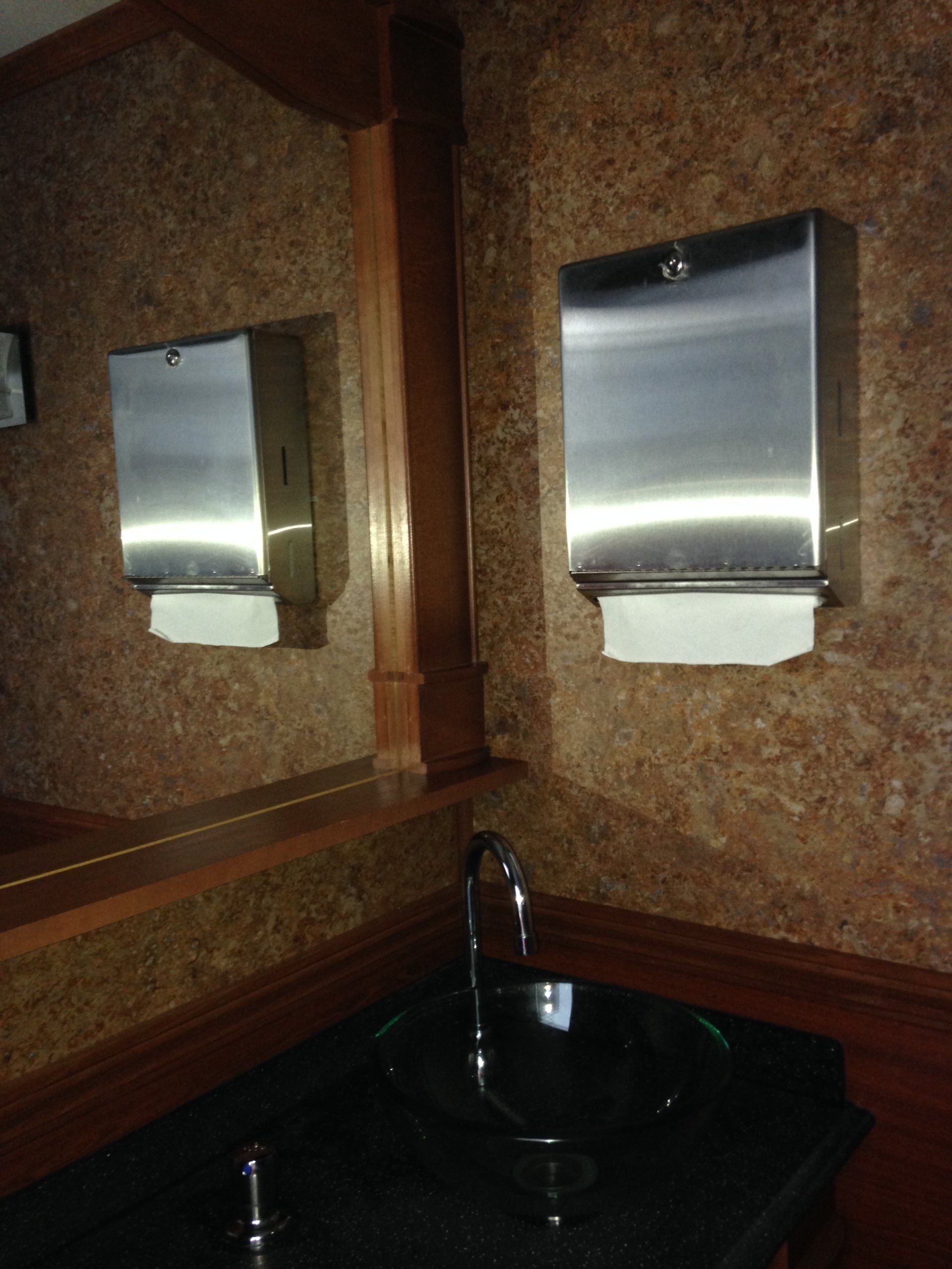 A bathroom with two paper towel dispensers and a sink