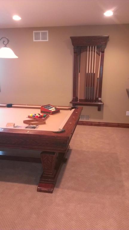 Game room with a pool table, carpeted floor, beige walls, and a window with dark wood blinds.