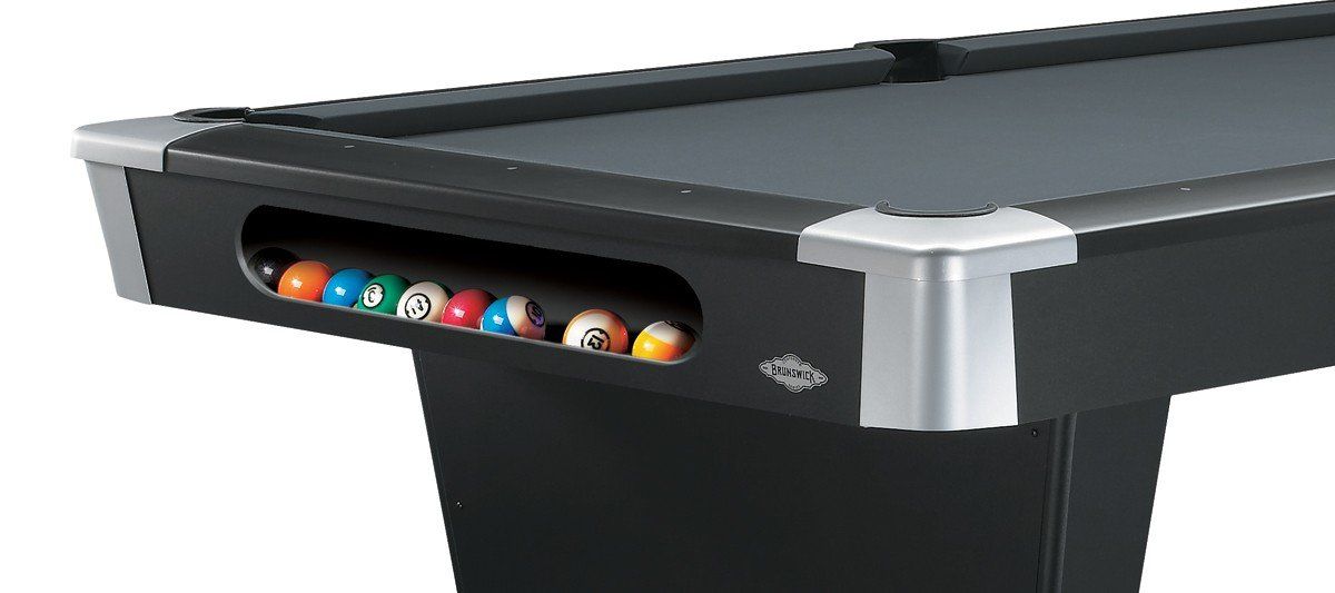 Black pool table corner with colorful billiard balls racked in the side pocket opening