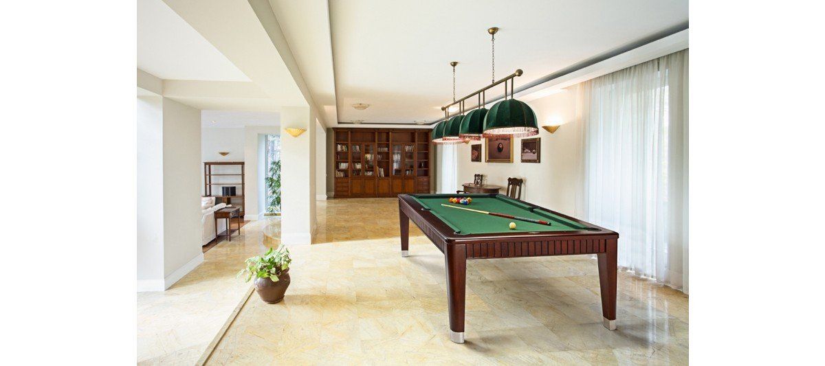 Bright game room with a pool table, wood cabinets, and large windows with sheer curtains.