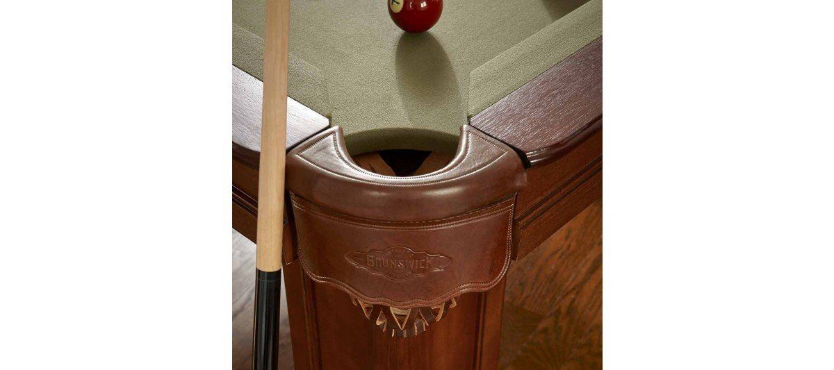 Close-up of a pool table corner pocket with a red ball near the cushion