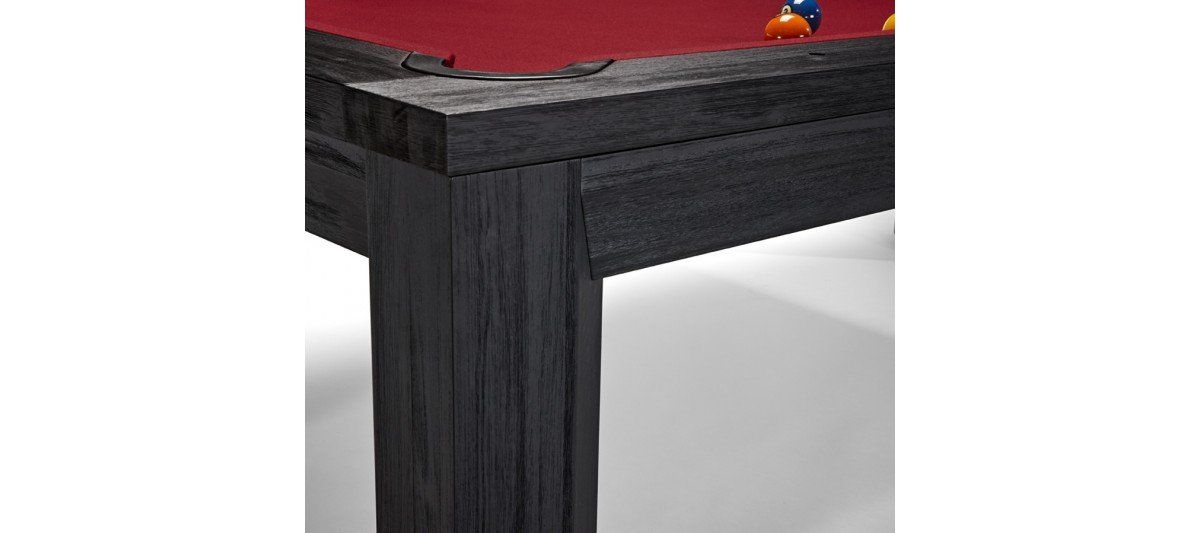 Close-up of a dark wooden table corner with a red tabletop and a small colorful object on top