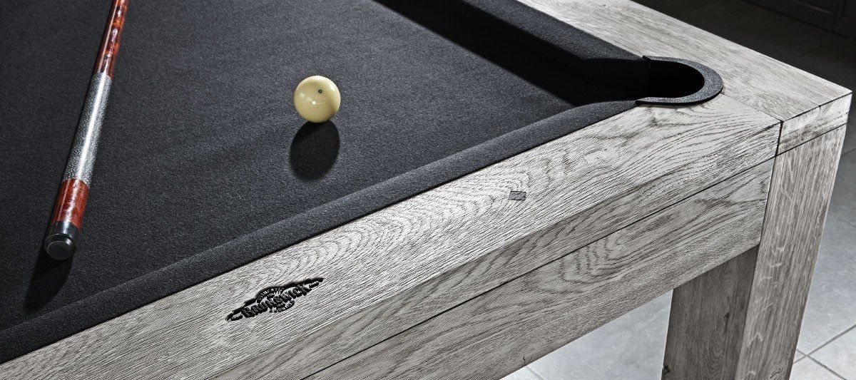 A billiards table with a cue stick and a yellow ball on the felt near the corner pocket.