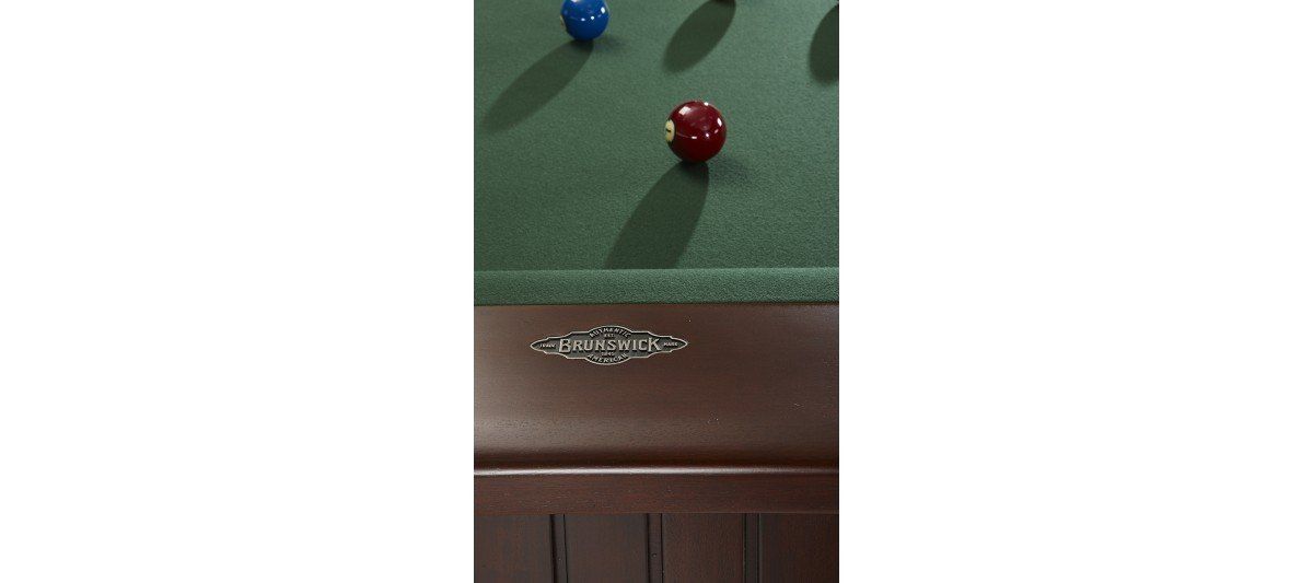 Blue and red billiard balls on green felt above a wooden cabinet with a small decorative flower arrangement
