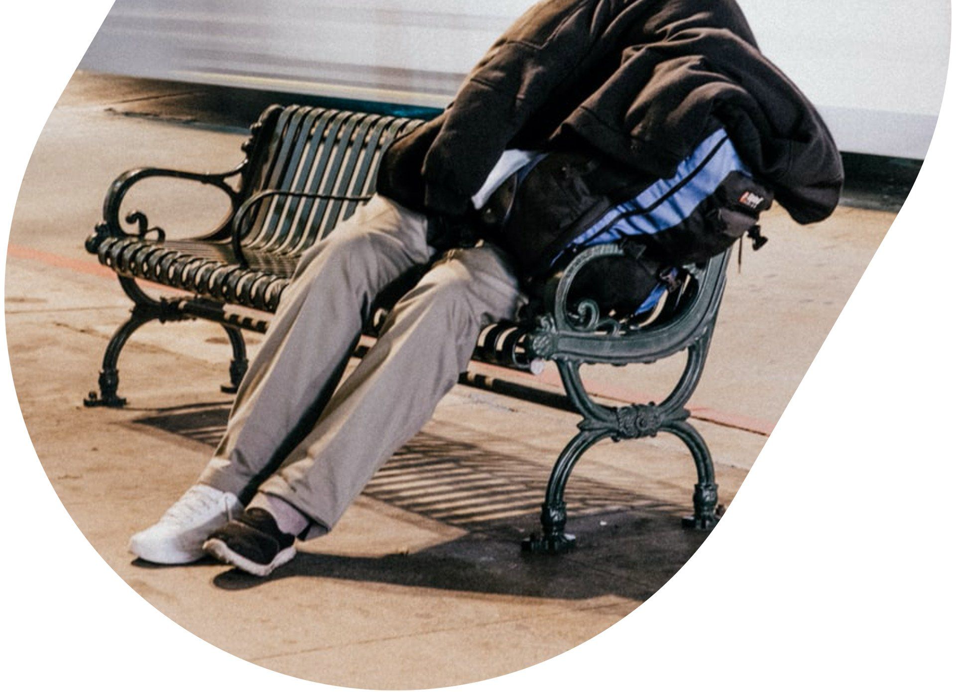 A person is sitting on a park bench with their legs crossed