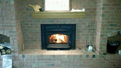 A brick fireplace with a wood stove in it.