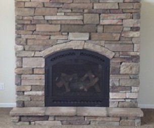 A stone fireplace with a black door in a living room.