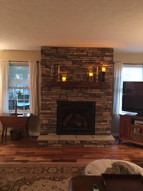 A living room with a stone fireplace and a flat screen tv