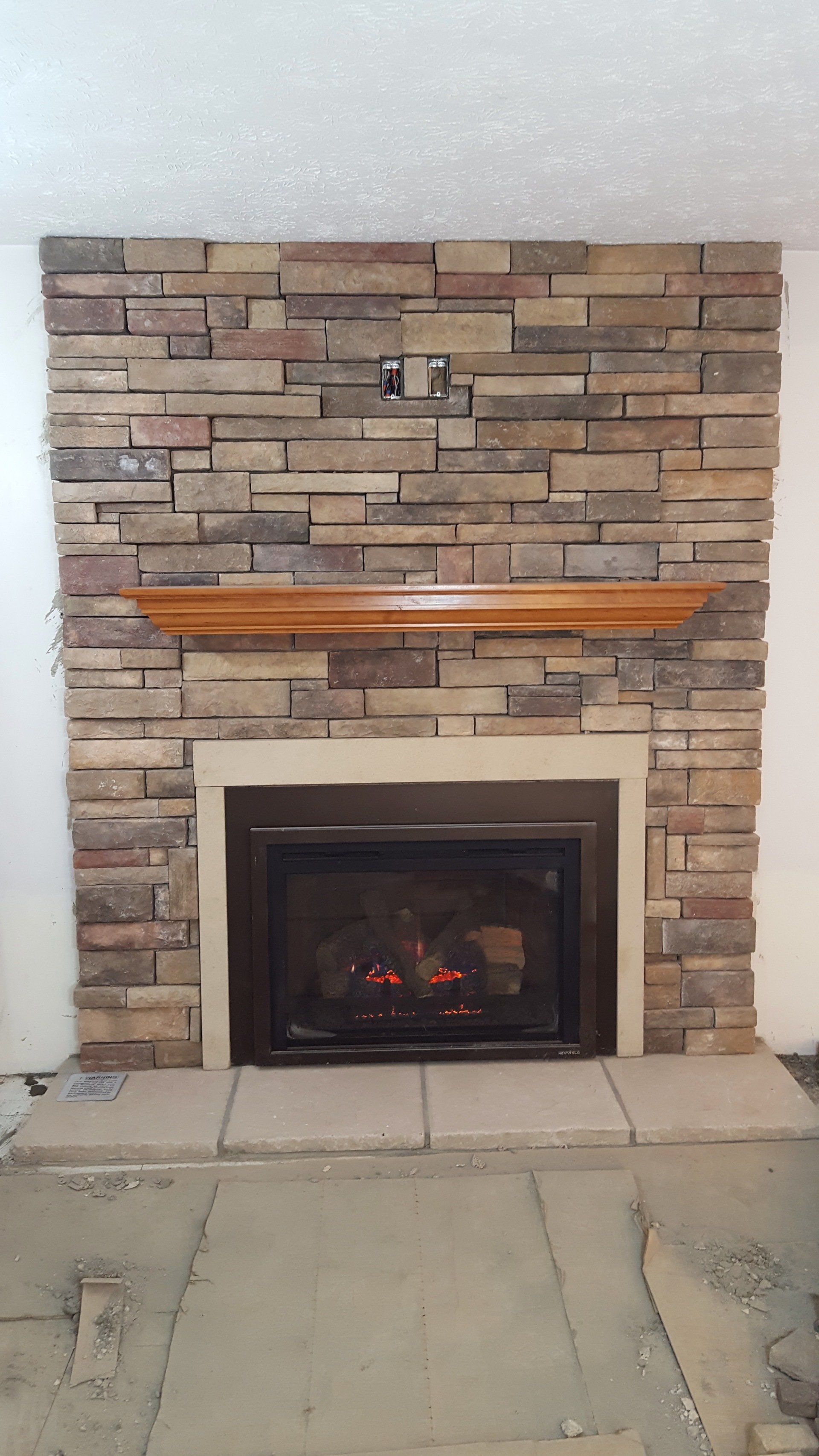A fireplace with a brick wall and a wooden mantle