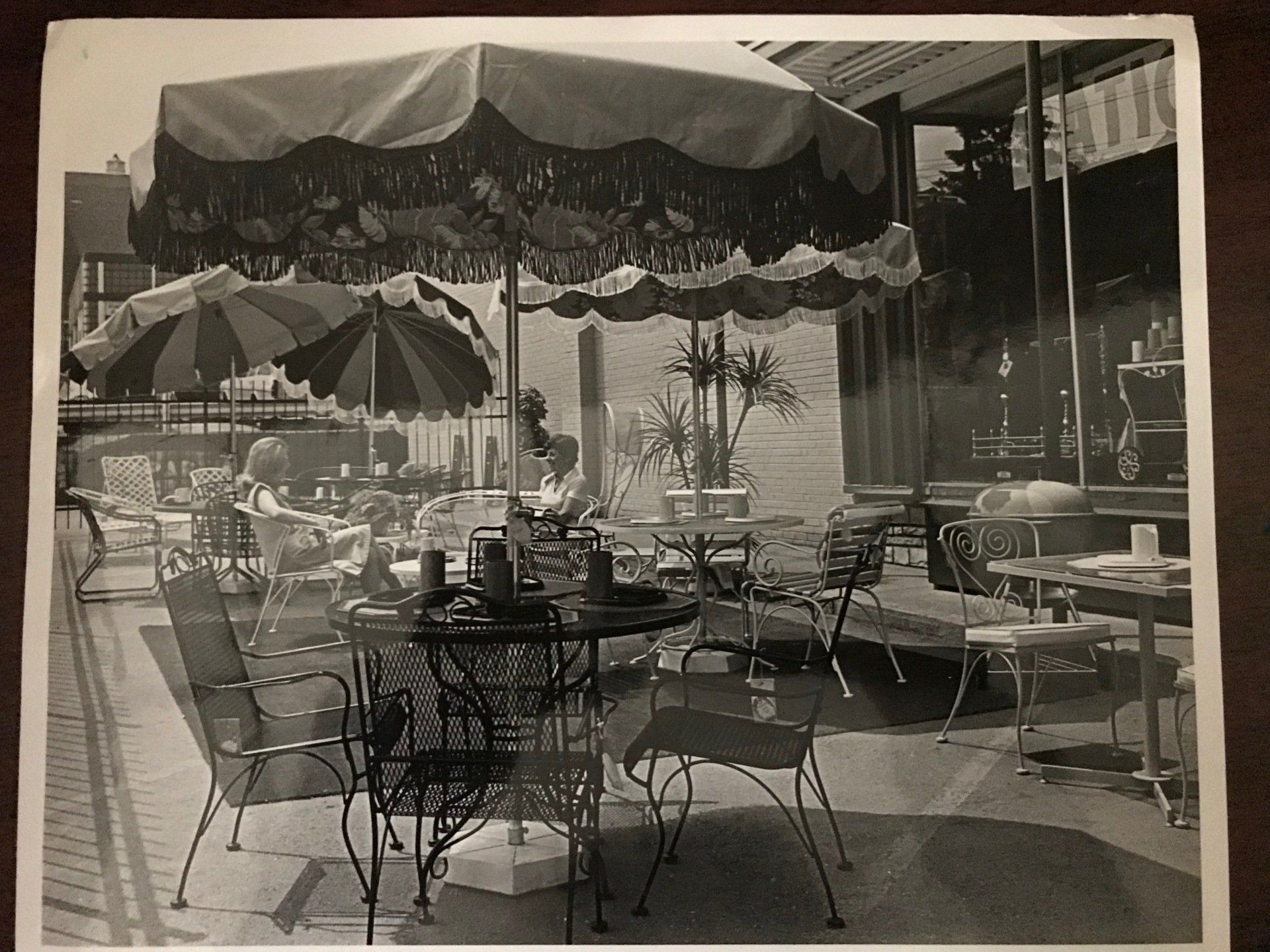 A black and white photo of tables and chairs under umbrellas