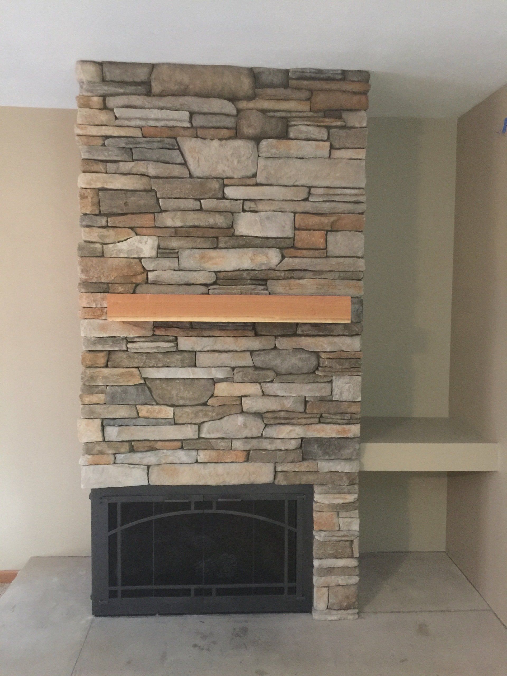 A stone fireplace with a wooden mantle in a living room.
