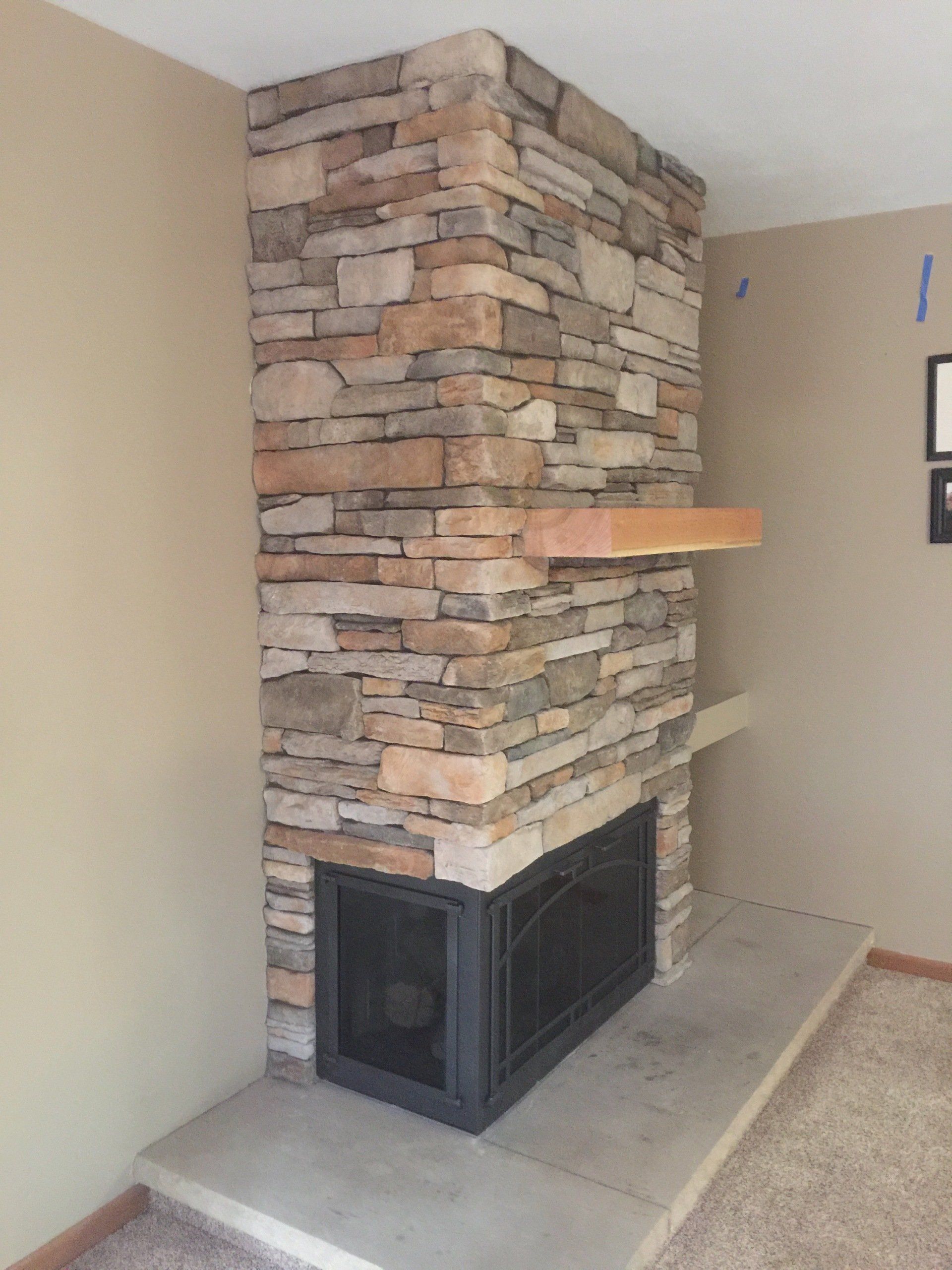 A stone fireplace with a black door in a living room