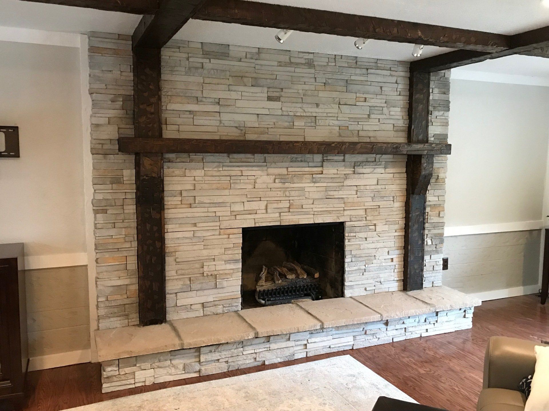 A living room with a brick fireplace and wooden beams