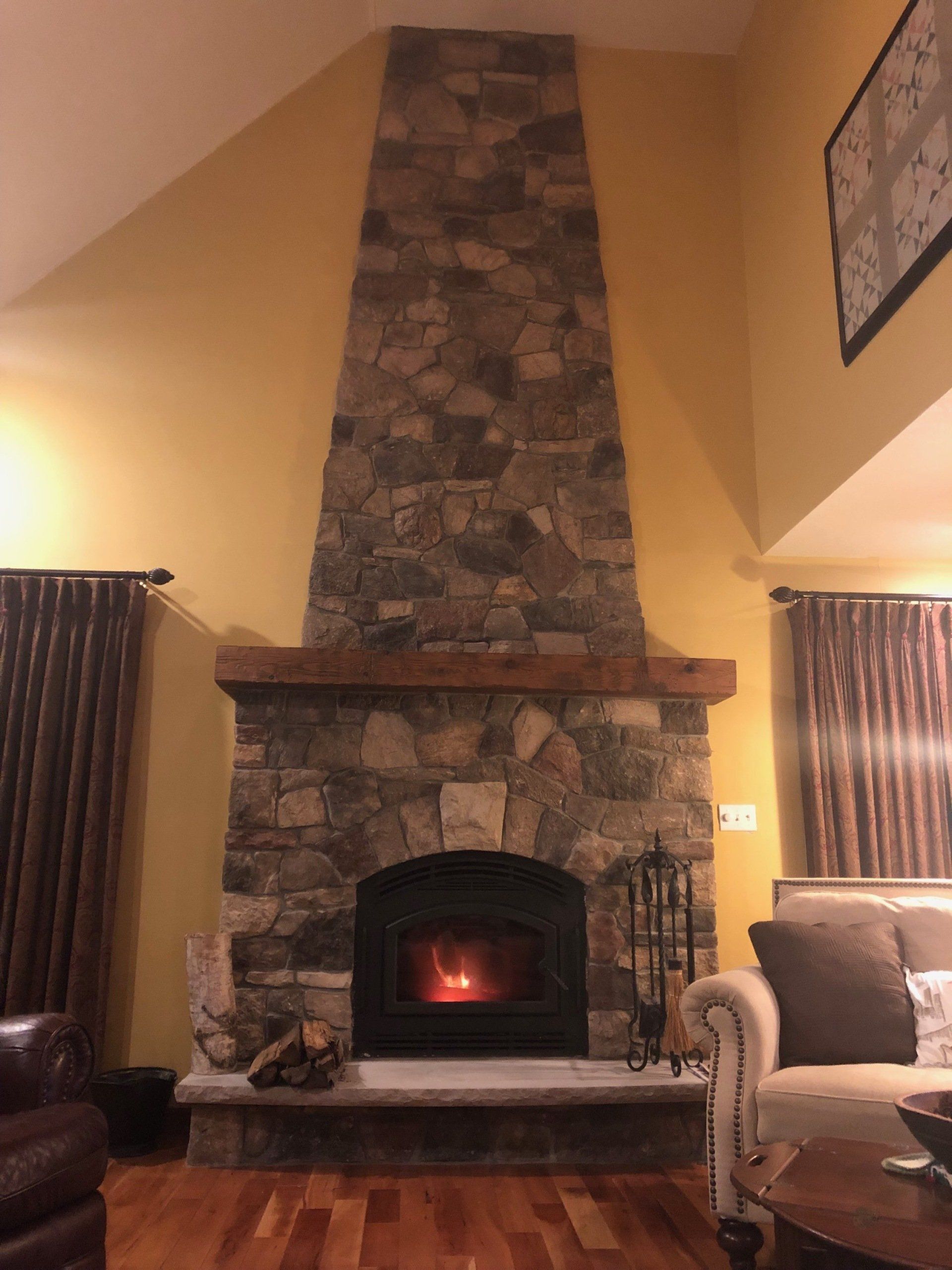 A living room with a large stone fireplace and a couch
