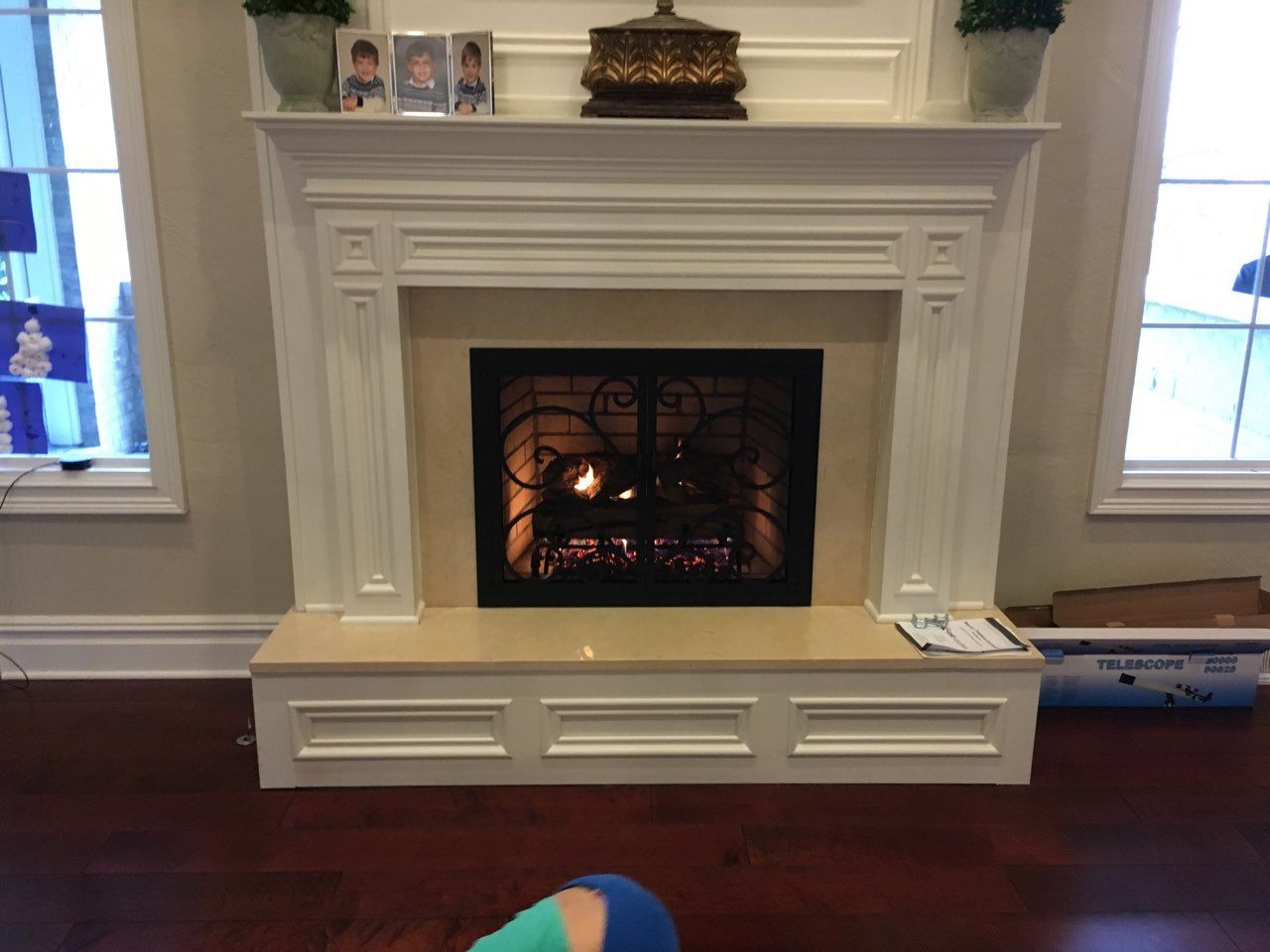 A fireplace in a living room with a person sitting in front of it.