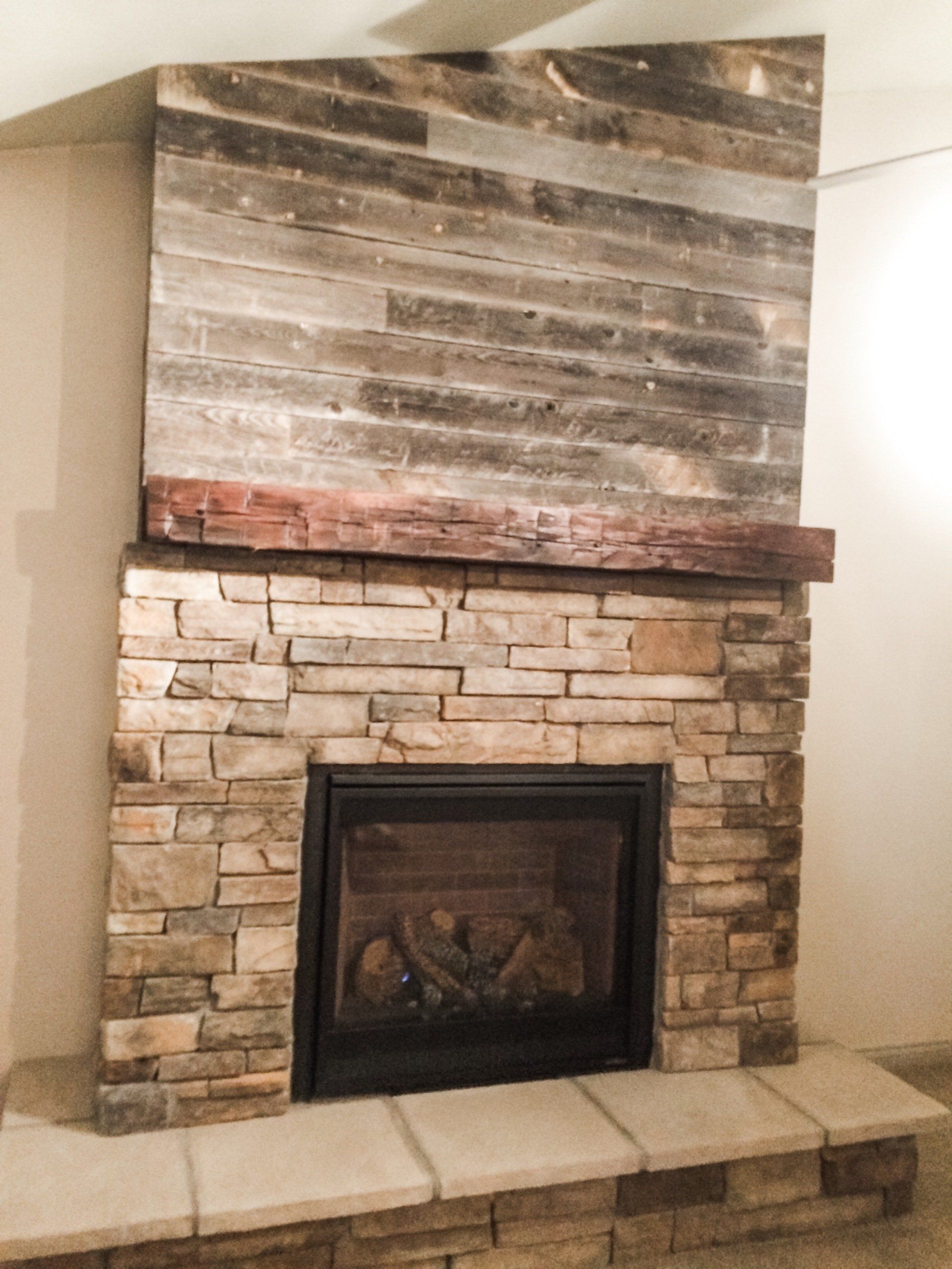 A stone fireplace with a wooden mantle in a living room