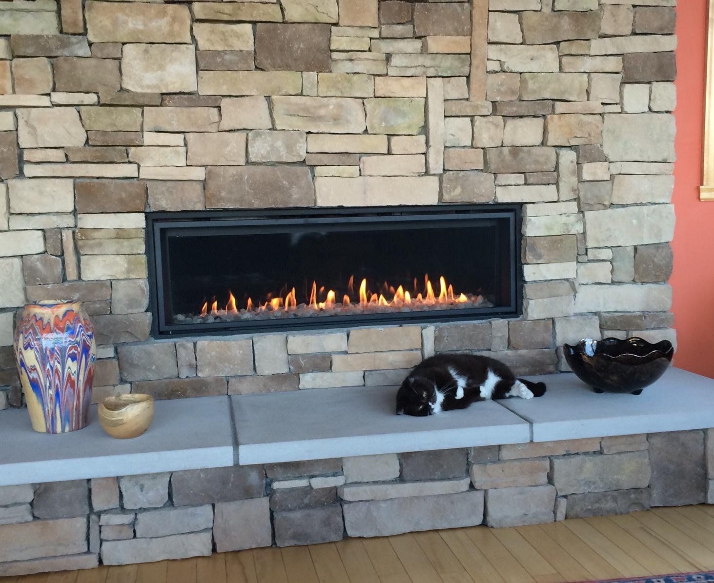 A cat laying on a bench in front of a fireplace