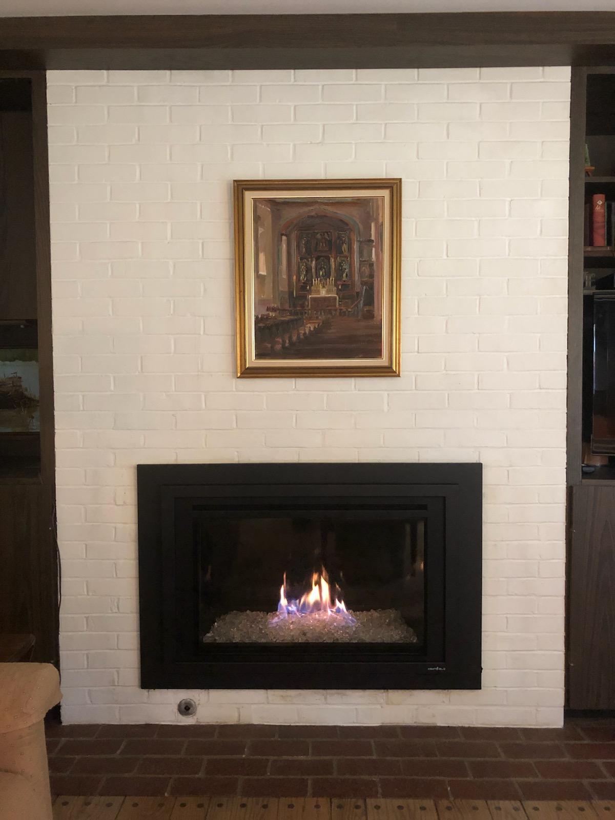 A fireplace with a picture above it in a living room.