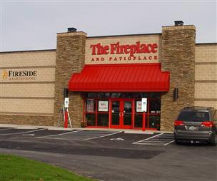 A car is parked in front of a store called the fireplace and patio place