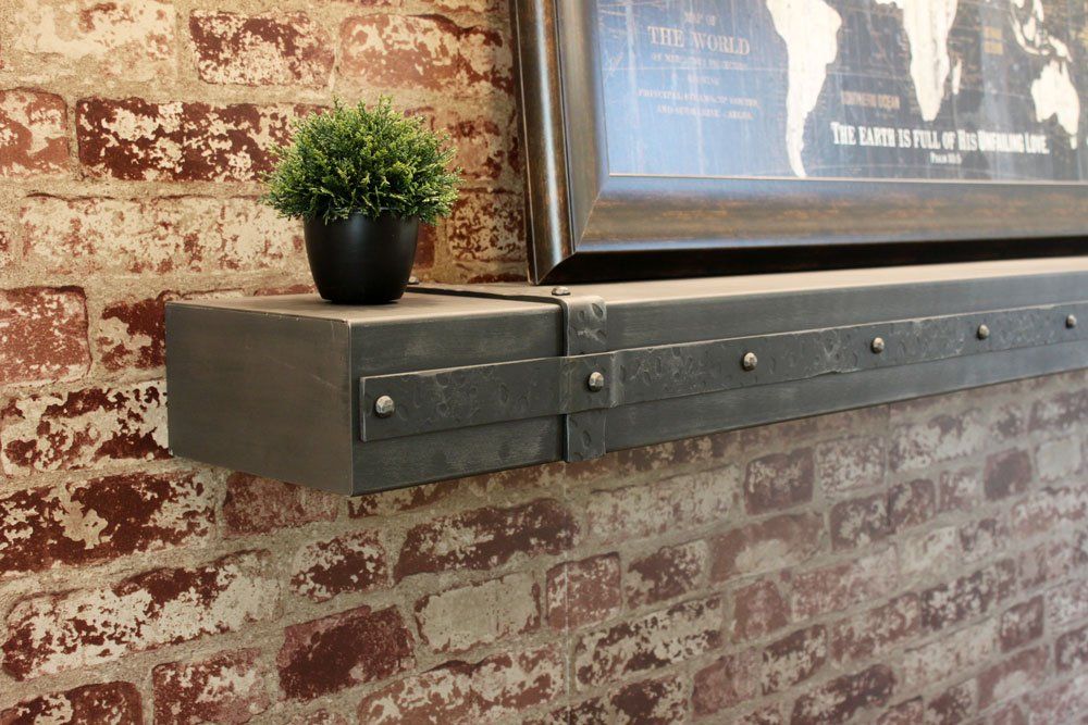 A brick wall with a metal mantle and a picture on it.