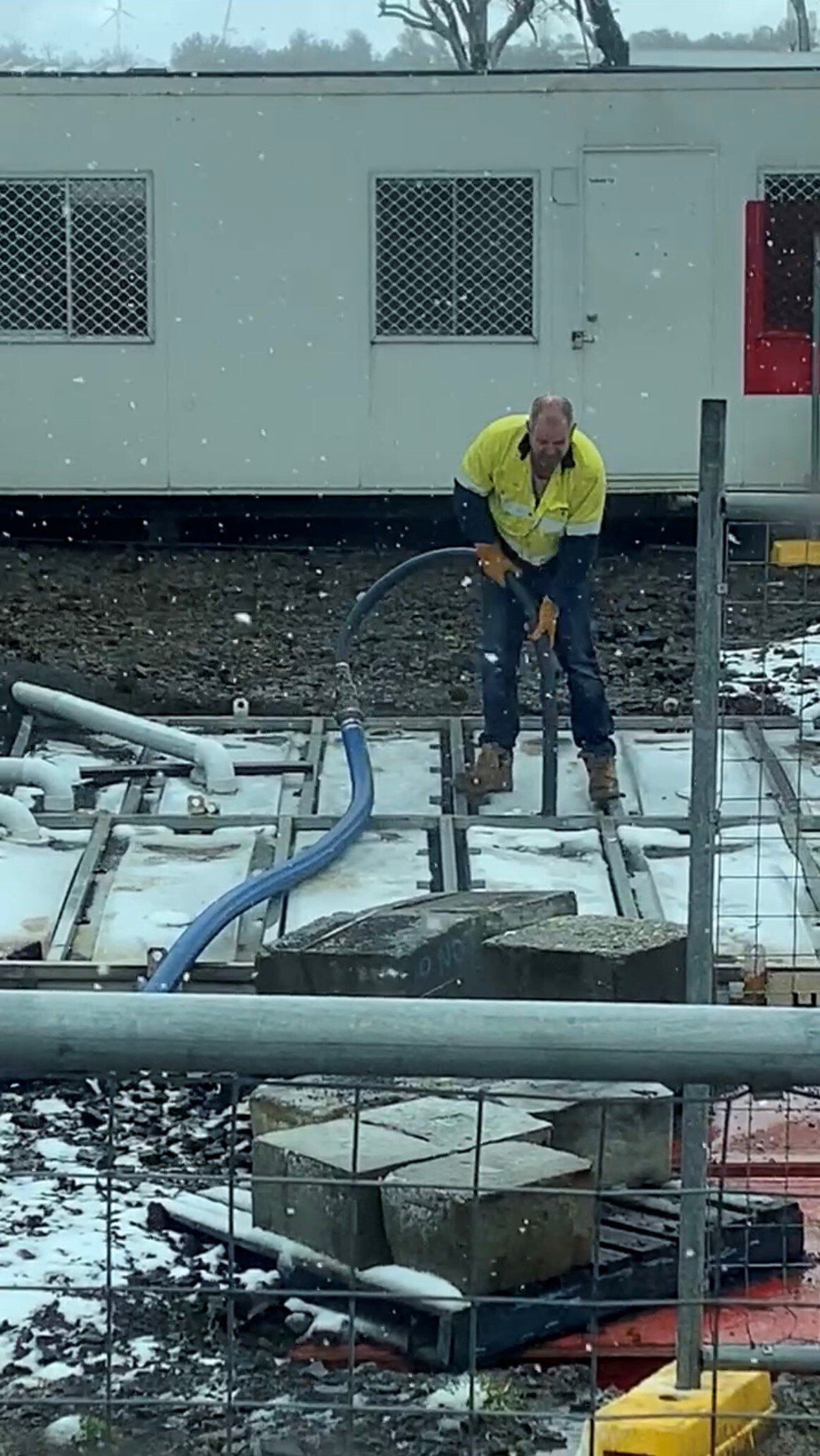 Construction worker using a jackhammer outdoors in snowy conditions.