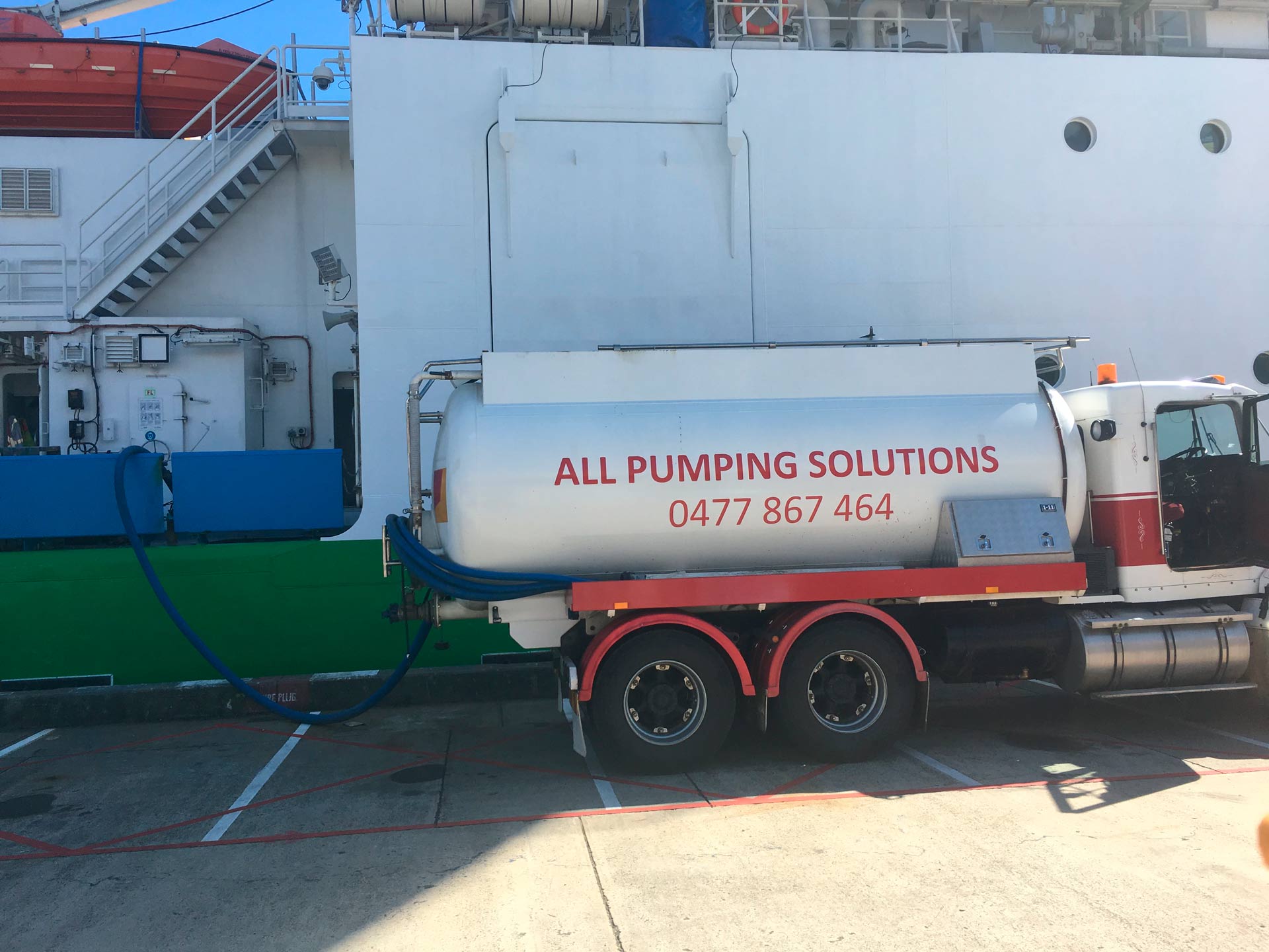 Tanker truck pumping liquid to a ship; the truck has