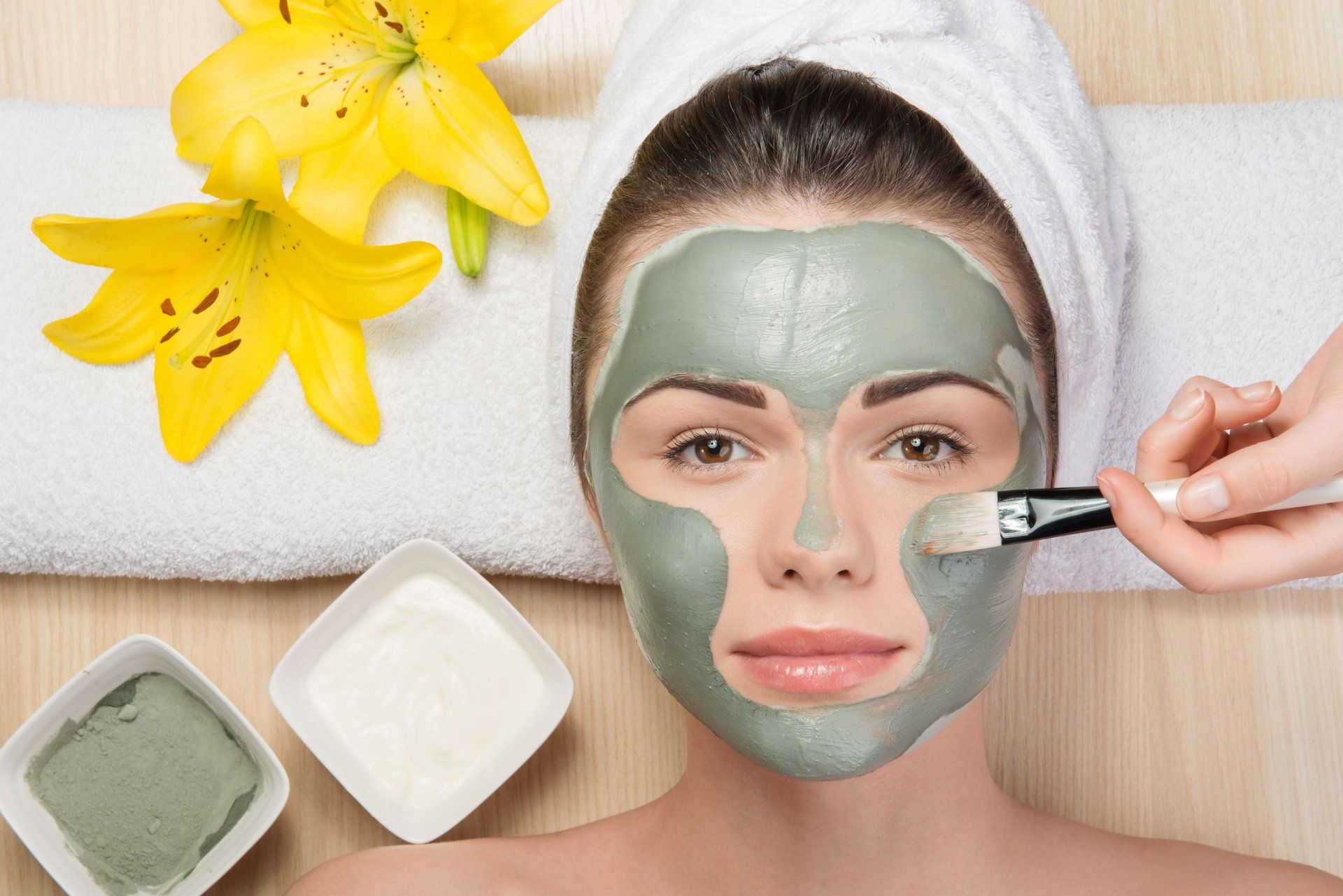 a woman is getting a clay mask on her face .