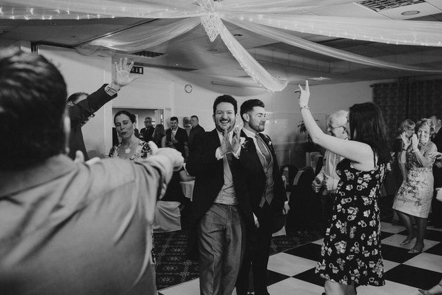 a black and white photo of a group of people dancing at a wedding reception .